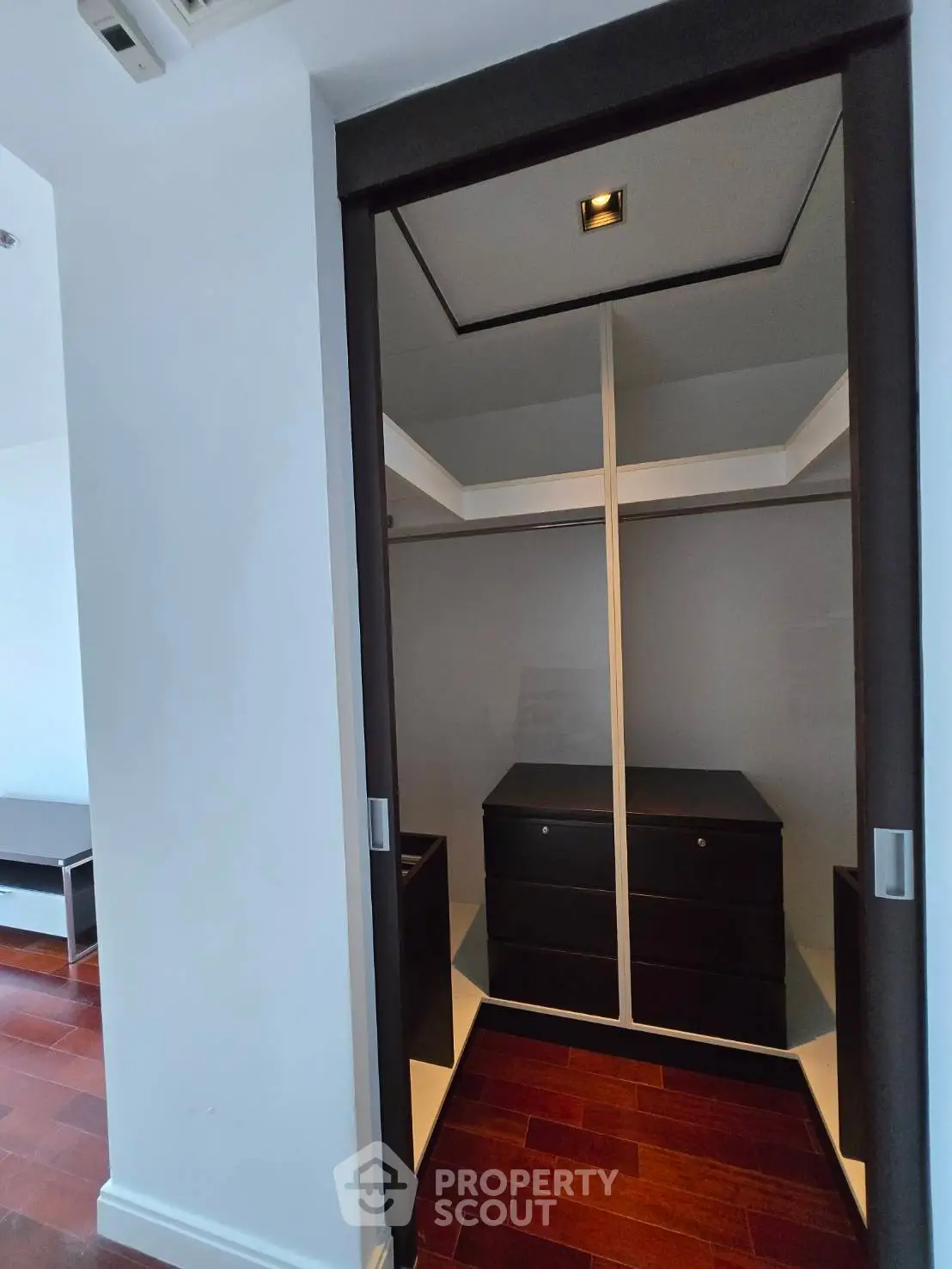 Spacious walk-in closet with elegant wooden flooring and ample storage space.