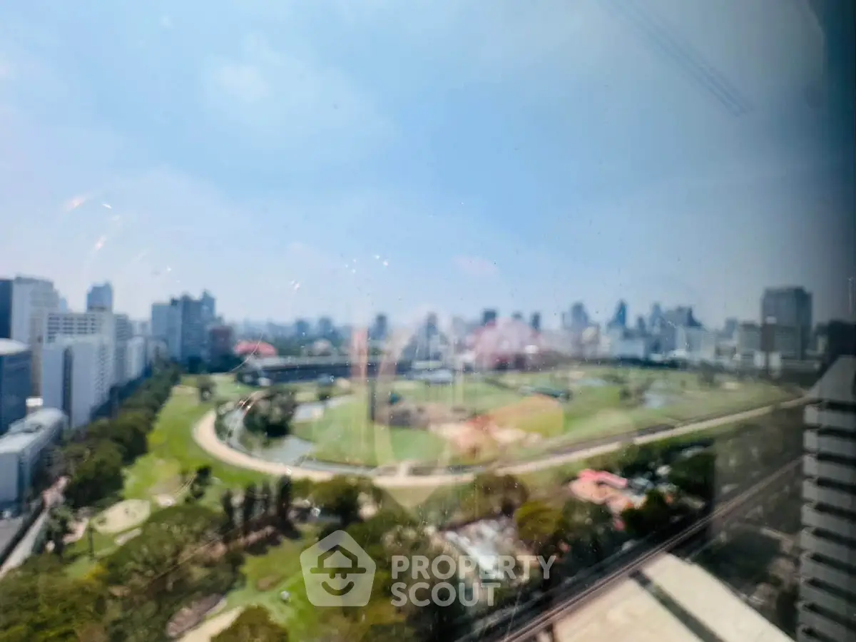 Stunning cityscape view from high-rise building overlooking lush green park and skyline.