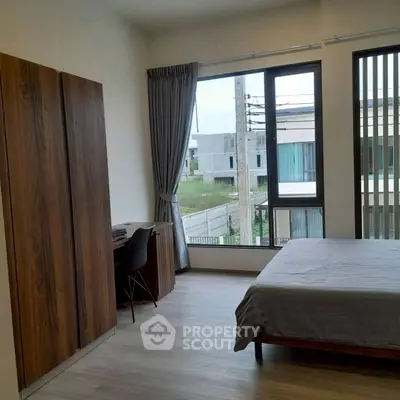 Modern bedroom with large window and stylish furniture in a contemporary home.