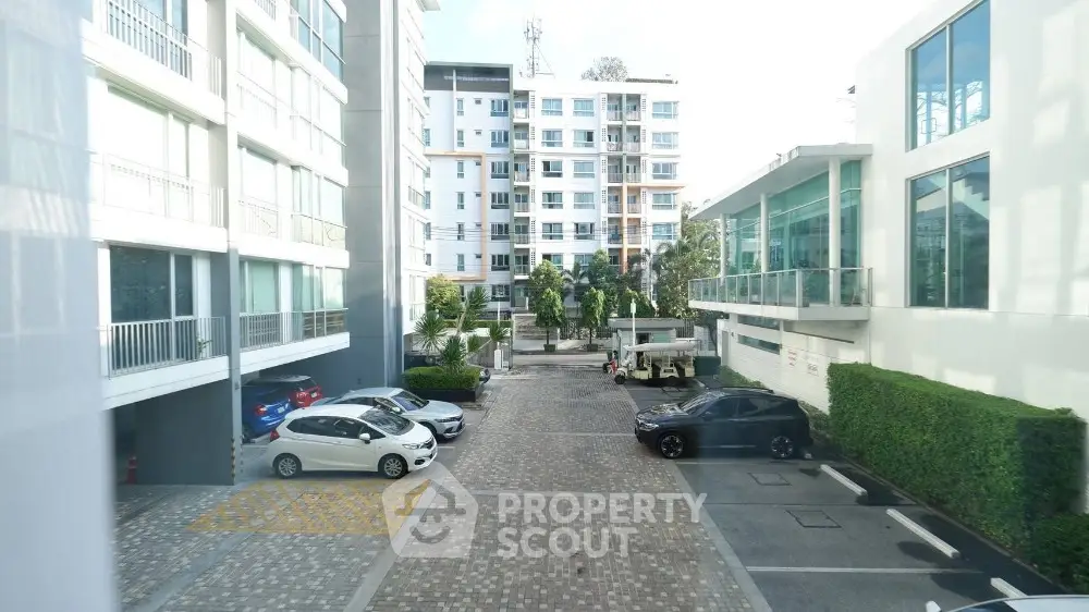 Modern apartment complex with spacious parking area and lush greenery