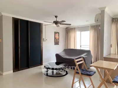 Spacious living room with modern decor and natural light, featuring a ceiling fan and cozy seating area.
