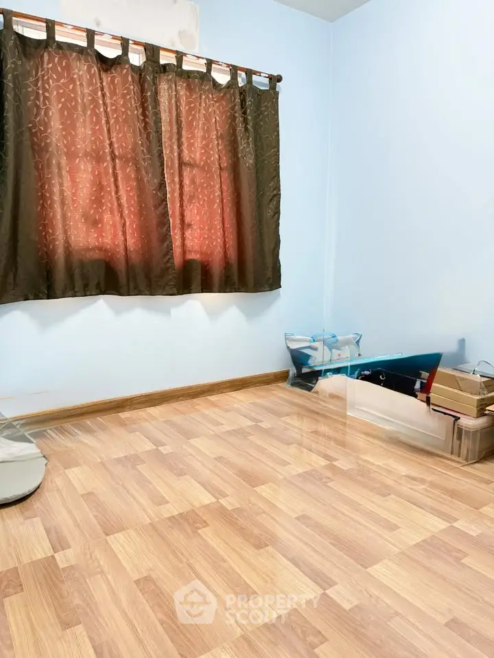 Spacious empty room with wooden flooring and window curtains