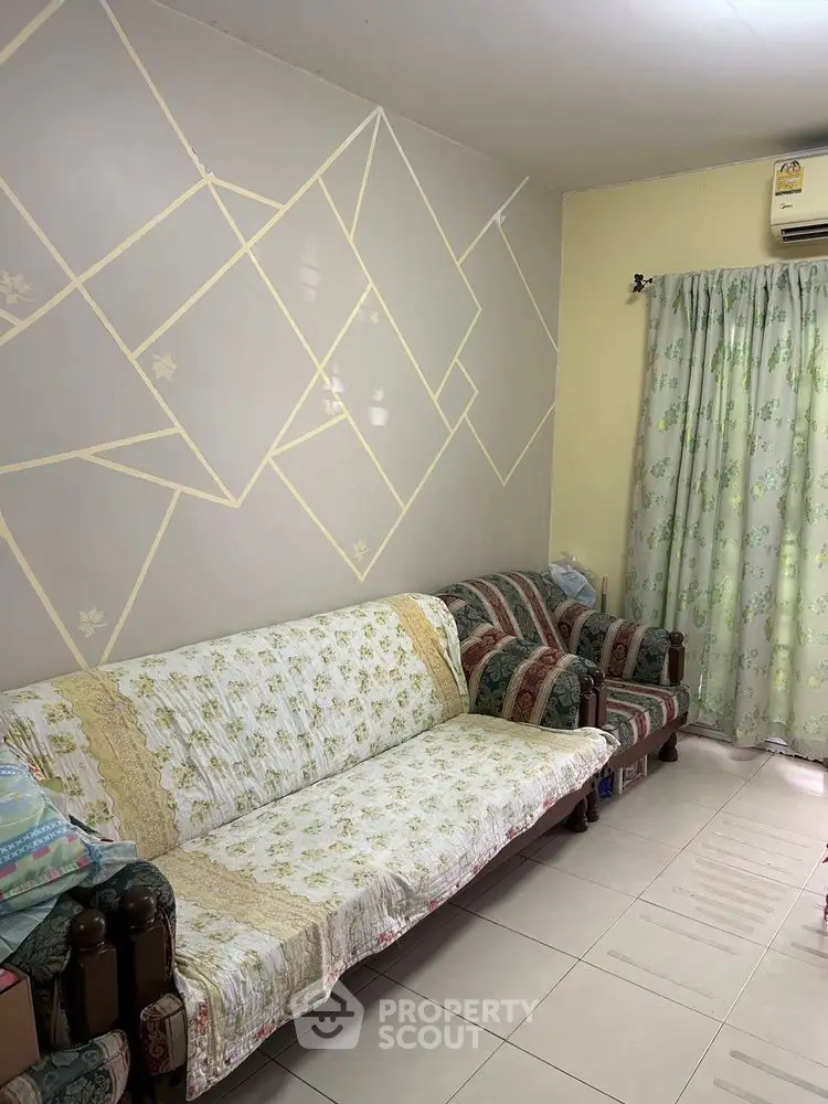 Cozy living room with patterned wall and floral curtains, featuring comfortable seating.