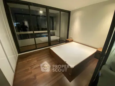 Modern bedroom with wooden flooring and large glass windows in a stylish apartment.