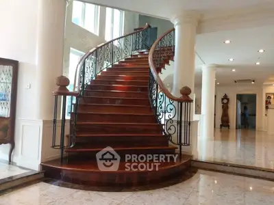 Luxurious grand staircase in elegant home with polished wooden steps and ornate railing.