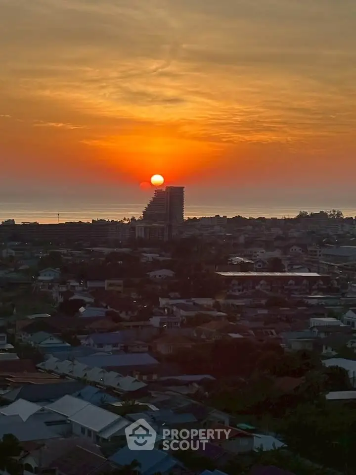 Stunning sunset view over cityscape with distant ocean horizon, perfect for serene living.