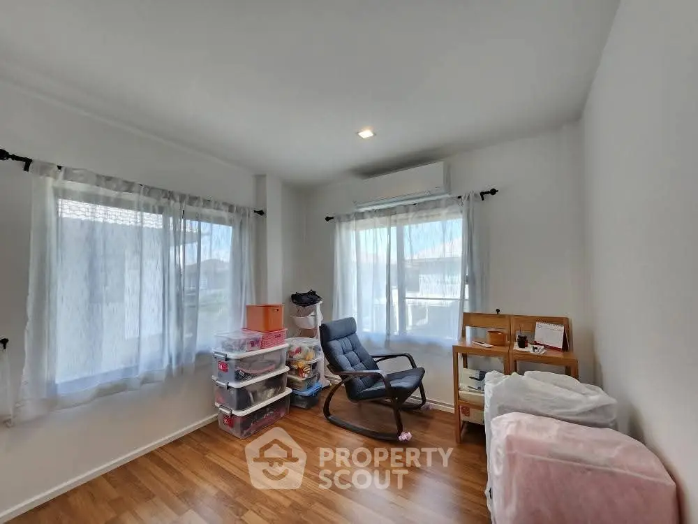 Bright room with wooden flooring, rocking chair, and storage boxes, ideal for versatile use.