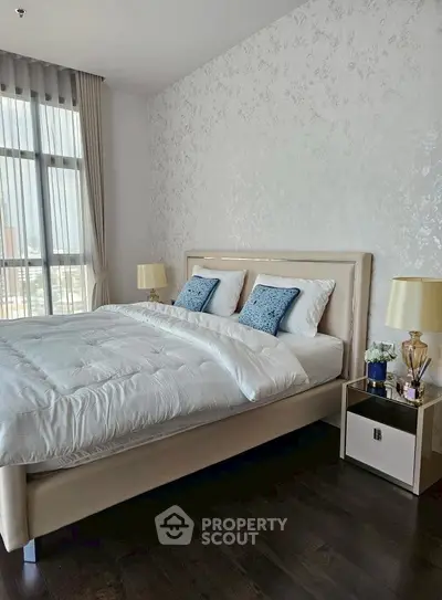 Luxurious bedroom with elegant decor and large window offering natural light.