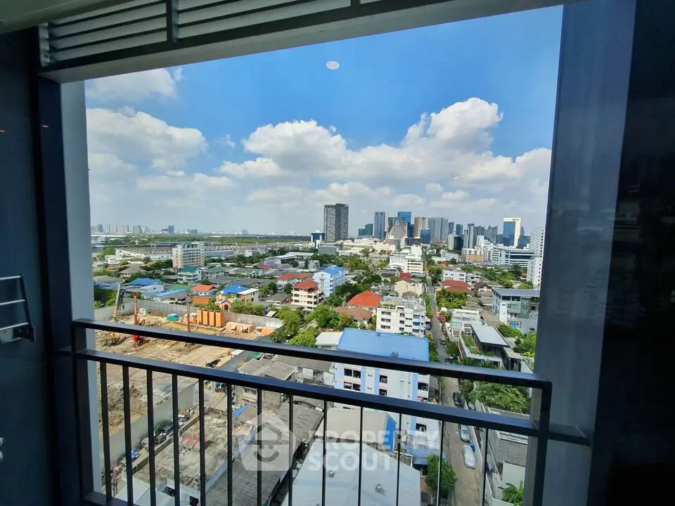 Stunning cityscape view from a high-rise balcony with clear blue skies and urban skyline.