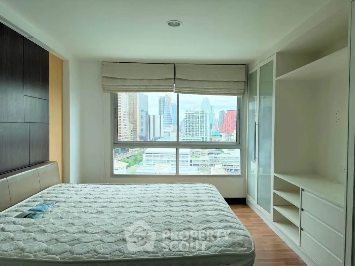 Spacious bedroom with city view, featuring large window and built-in wardrobe.