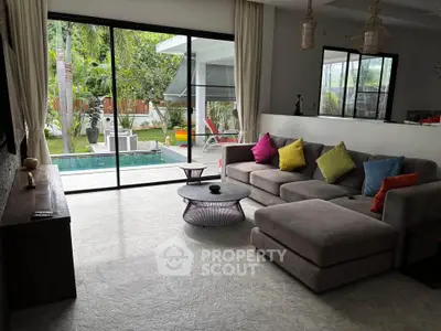 Spacious living room with modern decor and pool view, perfect for relaxation and entertaining.