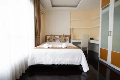 Modern bedroom with stylish decor and natural light, featuring a cozy bed and sleek furniture.