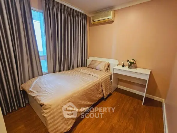 Cozy bedroom with single bed, elegant curtains, and wooden flooring in a modern apartment.