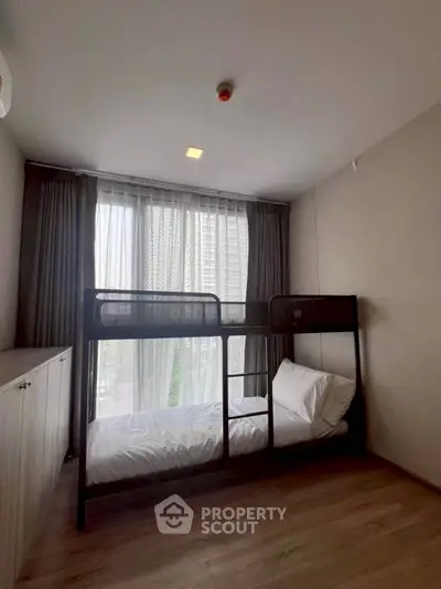 Cozy bedroom with bunk bed and large window offering natural light.