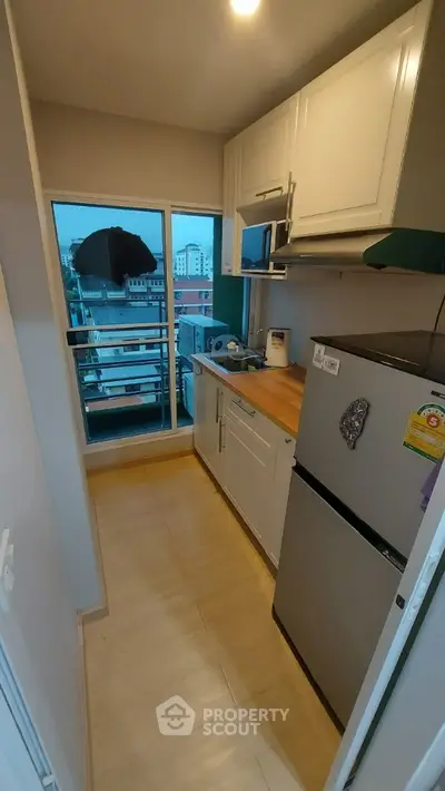 Compact kitchen with modern appliances and city view from window