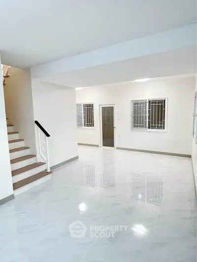 Spacious modern interior with glossy tiled floors and staircase, ideal for contemporary living.