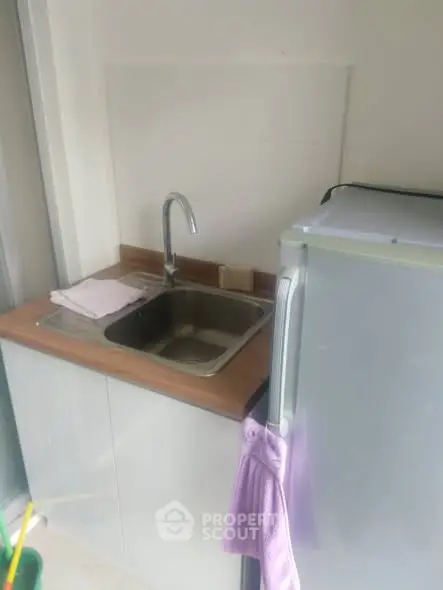 Compact kitchen corner with sink and fridge, ideal for small apartments.