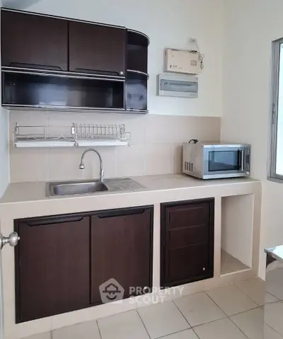 Compact kitchen with dark cabinets and microwave, ideal for small apartments