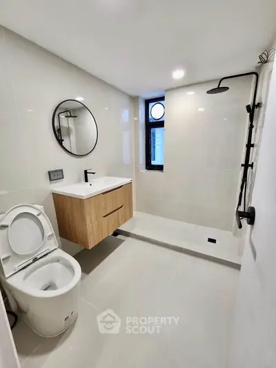 Modern bathroom with sleek fixtures and minimalist design, featuring a walk-in shower and stylish vanity.