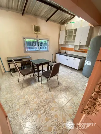 Cozy kitchen space with vintage floral tile flooring, classic white cabinetry, and a simple dining set, ideal for intimate family meals.