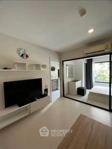 Modern living room with TV and view into cozy bedroom