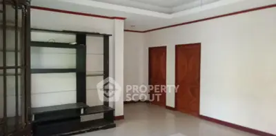 Spacious empty room with wooden doors and built-in shelving unit.