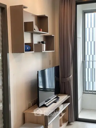 Modern living room with sleek TV setup and stylish shelving, featuring a view of the balcony.