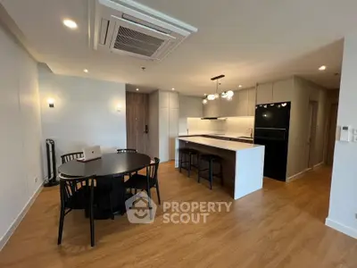 Modern open-layout kitchen and dining area with sleek design and wooden flooring.
