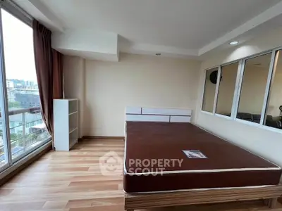 Spacious bedroom with large window and wooden flooring in modern apartment