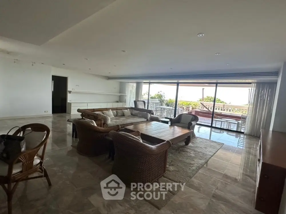 Spacious living room with elegant furniture and large windows offering a stunning view of the balcony.