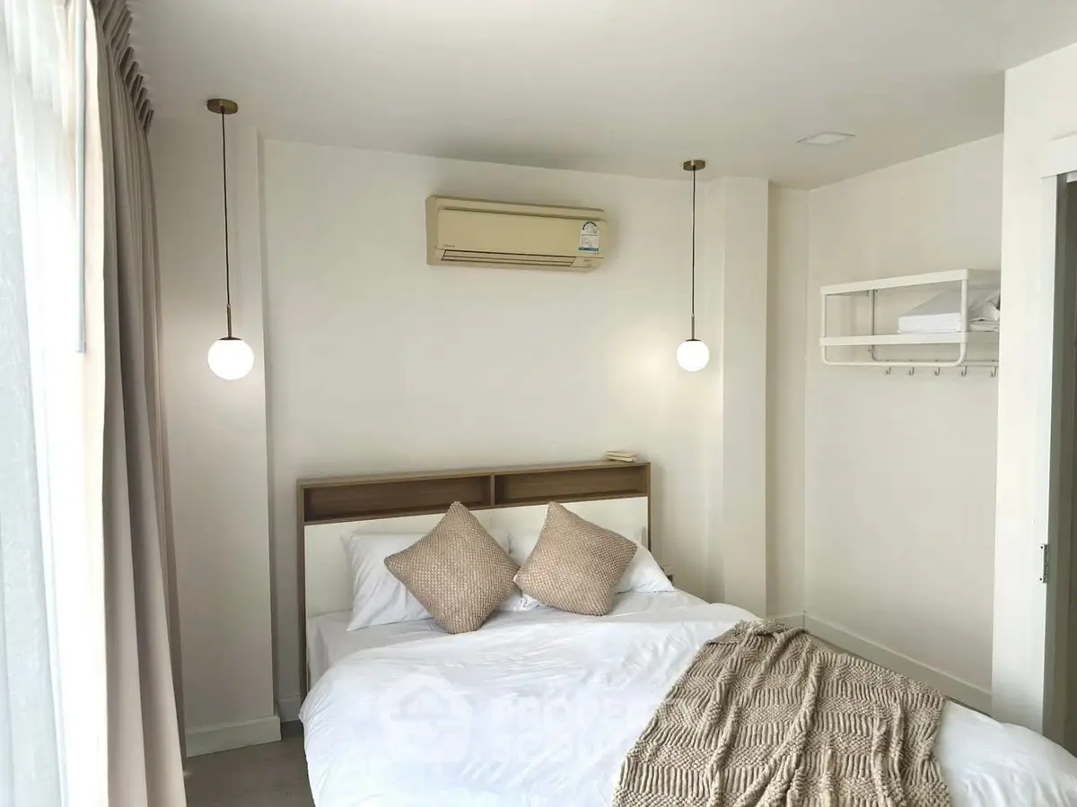 Cozy bedroom with modern decor and natural light, featuring a comfortable bed and stylish lighting.