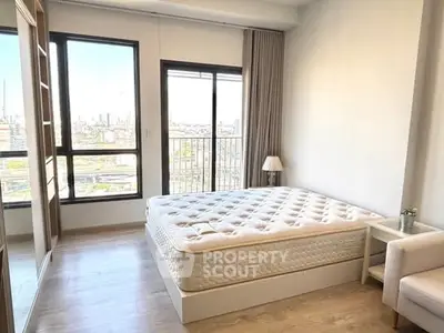 Bright bedroom with large windows and city view, featuring a comfortable bed and modern decor.