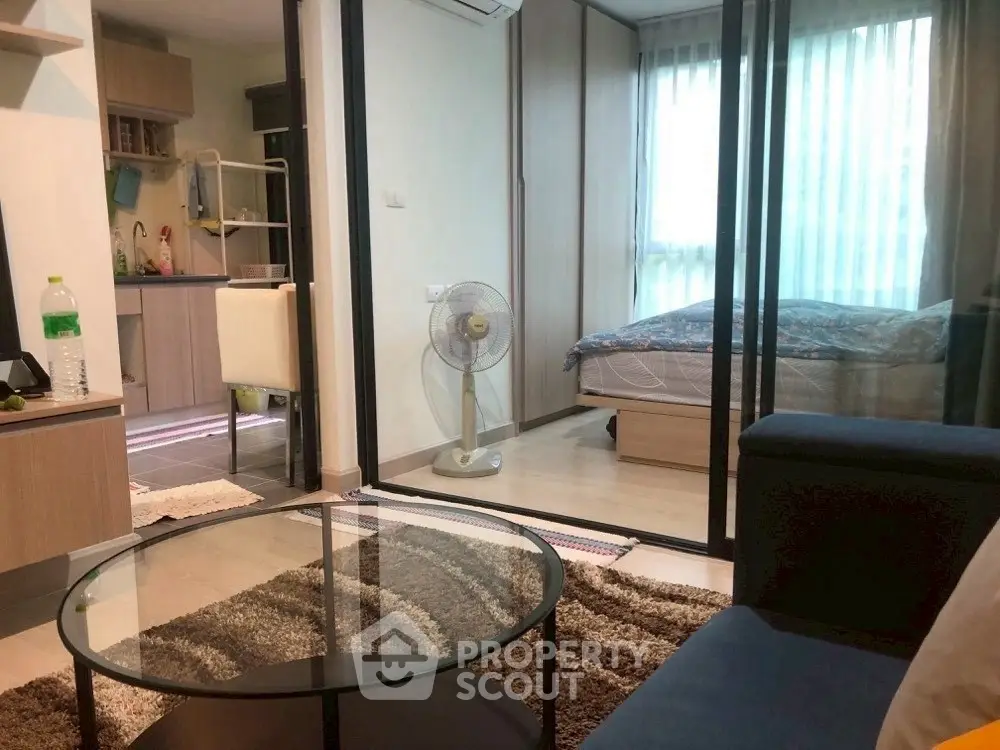 Cozy modern apartment with glass partition, stylish living area, and compact kitchen.
