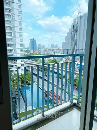Stunning city view from a high-rise balcony overlooking a pool and urban skyline.
