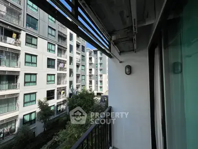 Modern apartment balcony with view of neighboring buildings and lush greenery.