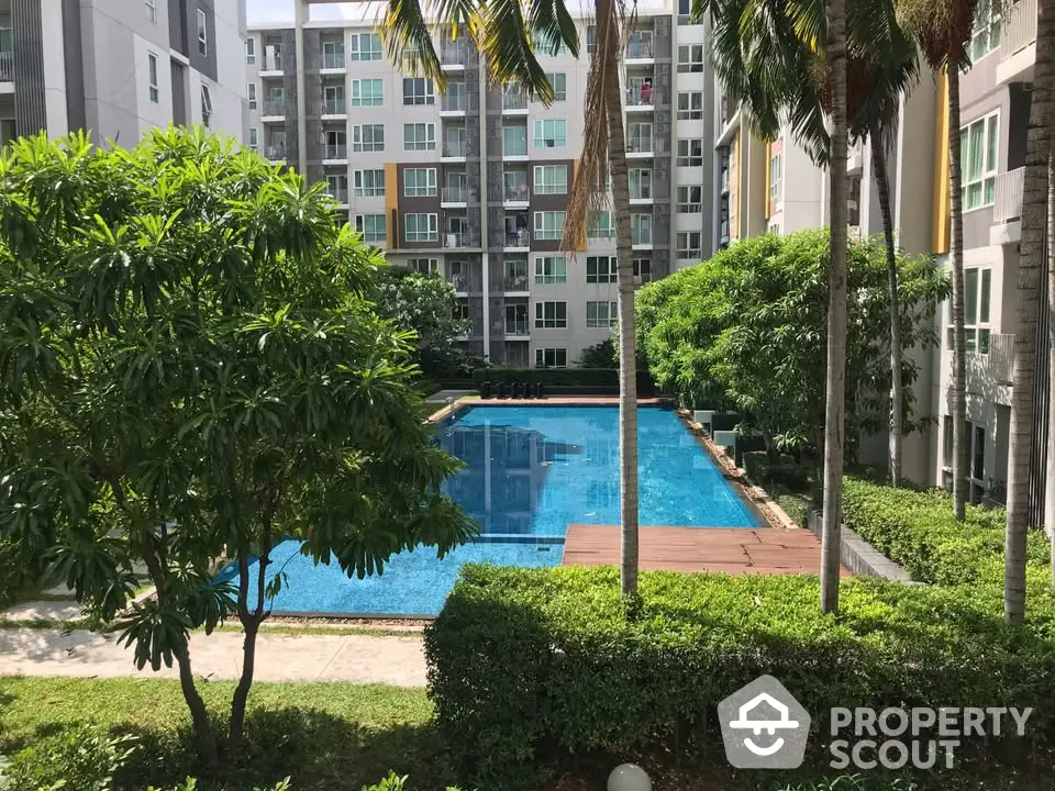 Luxurious condominium with a stunning pool surrounded by lush greenery and modern architecture.