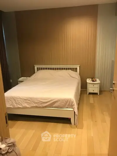 Cozy bedroom with wooden flooring and elegant bed setup in modern apartment.