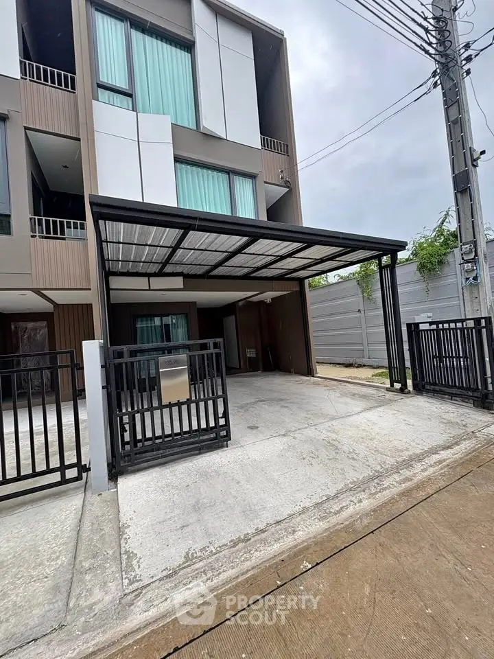 Modern townhouse exterior with gated driveway and sleek design.