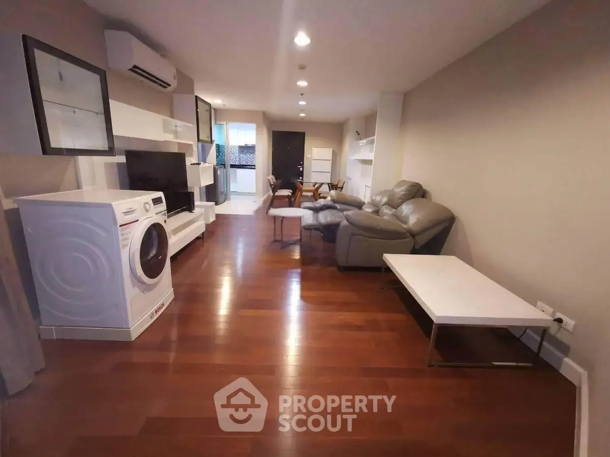 Spacious living room with modern furniture and washing machine, ideal for comfortable living.