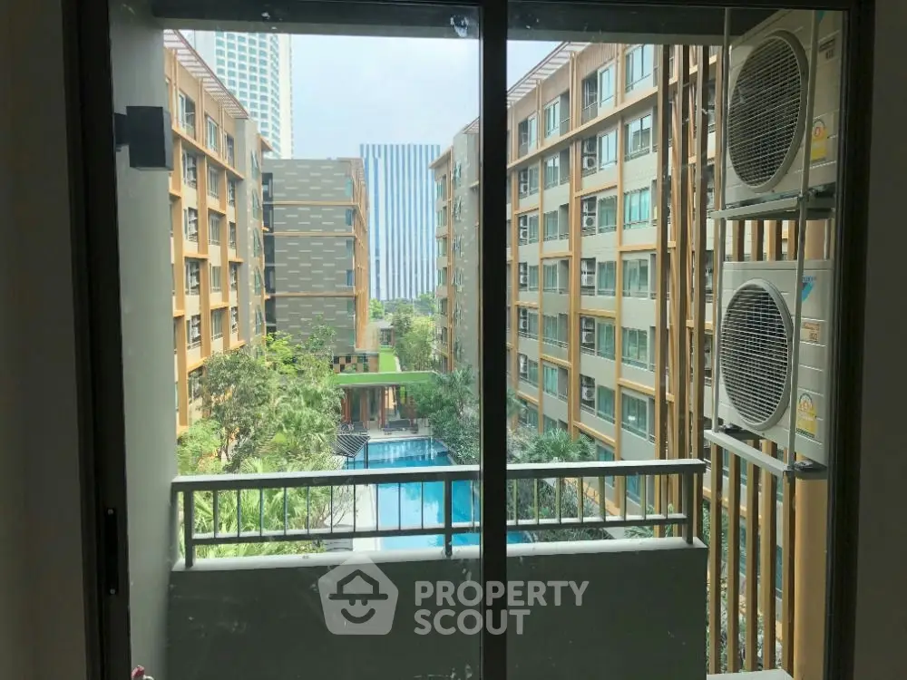 Modern apartment view with pool and garden from balcony, showcasing urban living elegance.