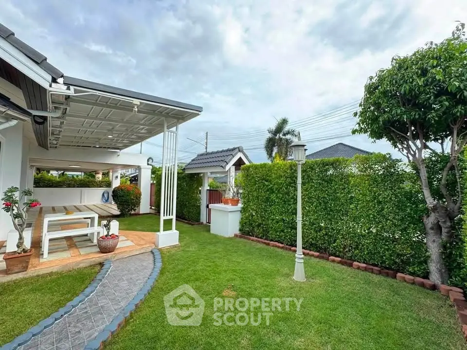 Charming garden view with patio in a suburban home, featuring lush greenery and cozy outdoor seating.
