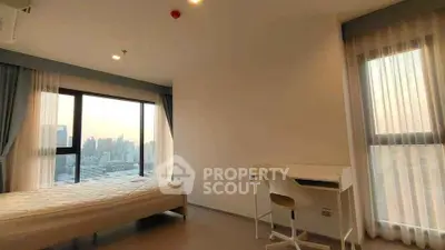 Spacious bedroom with city view and natural light, featuring a bed and study desk.