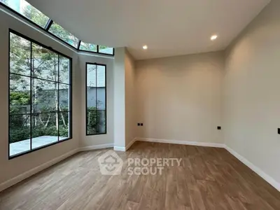 Spacious empty room with large windows and wooden flooring, perfect for customization.