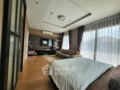 Spacious bedroom with modern decor and large windows offering natural light