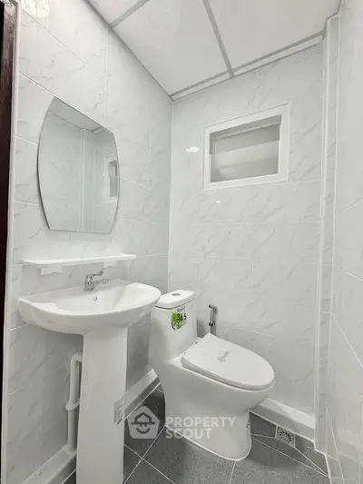 Modern bathroom with sleek white fixtures and elegant marble tiles.