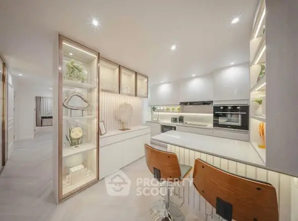 Modern kitchen with sleek design and open layout, featuring stylish bar stools and elegant lighting.