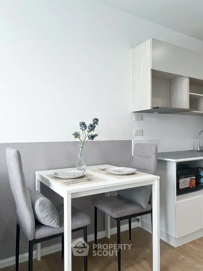 Modern kitchen with dining area featuring sleek white cabinetry and stylish gray chairs.