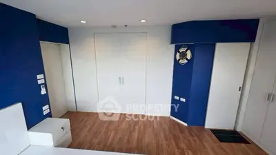 Modern room with blue walls and wooden flooring, featuring sleek white doors.