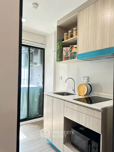 Modern kitchen with sleek cabinetry and built-in appliances, featuring a compact design and natural light.