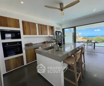 Modern kitchen with open layout and stunning ocean view, featuring sleek appliances and stylish island seating.